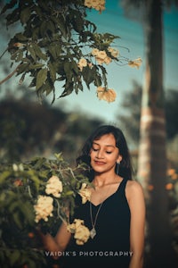 a woman is standing in front of a tree with flowers